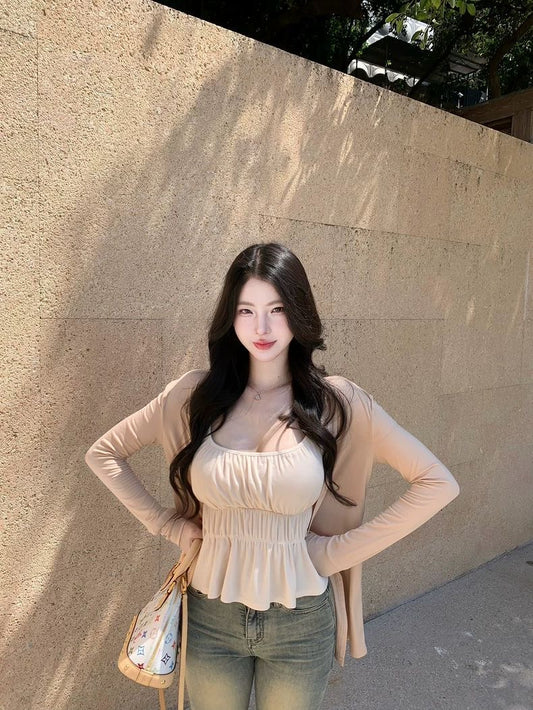 Woman posing against a beige wall with a neutral expression